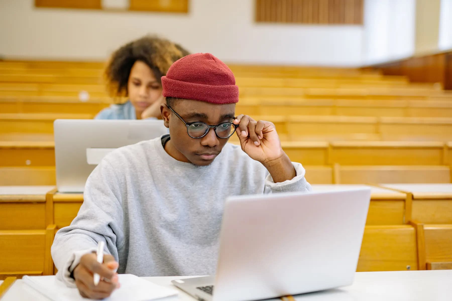 A student studying on a laptop in a lecture hall.